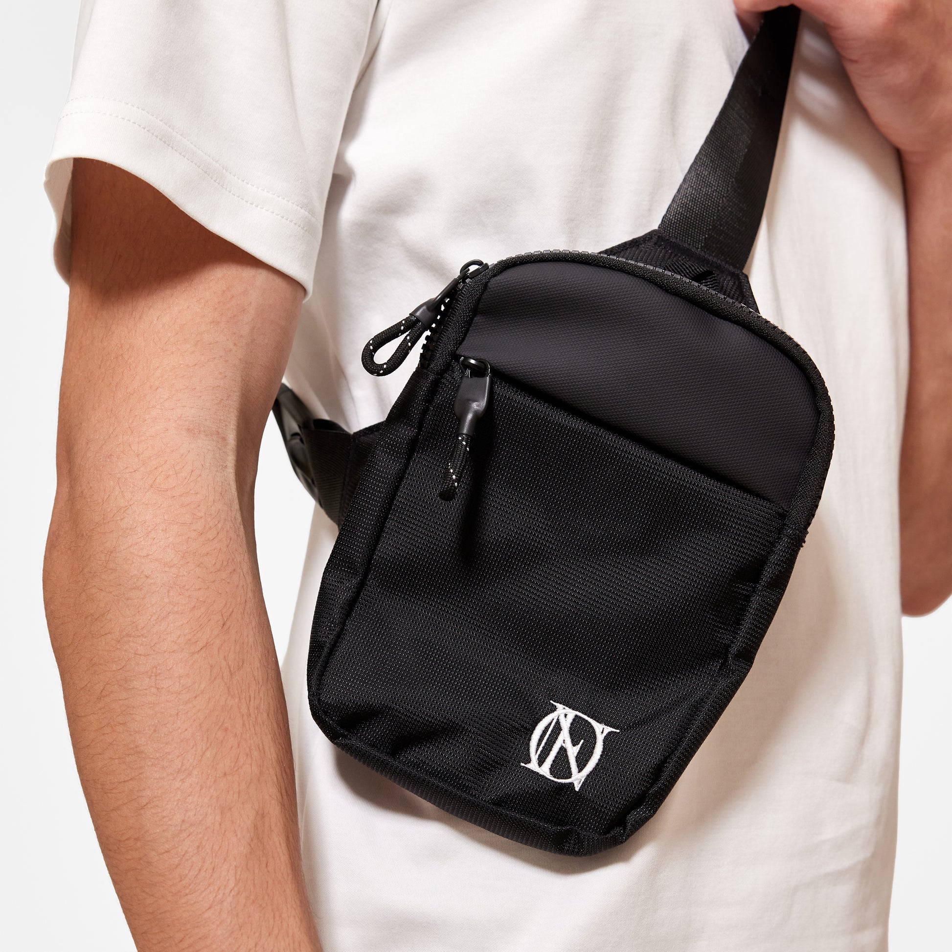 Close up of model wearing OG 'OFFEND' black crossbody bag with the white 'OFFEND'  logo in the bottom right corner