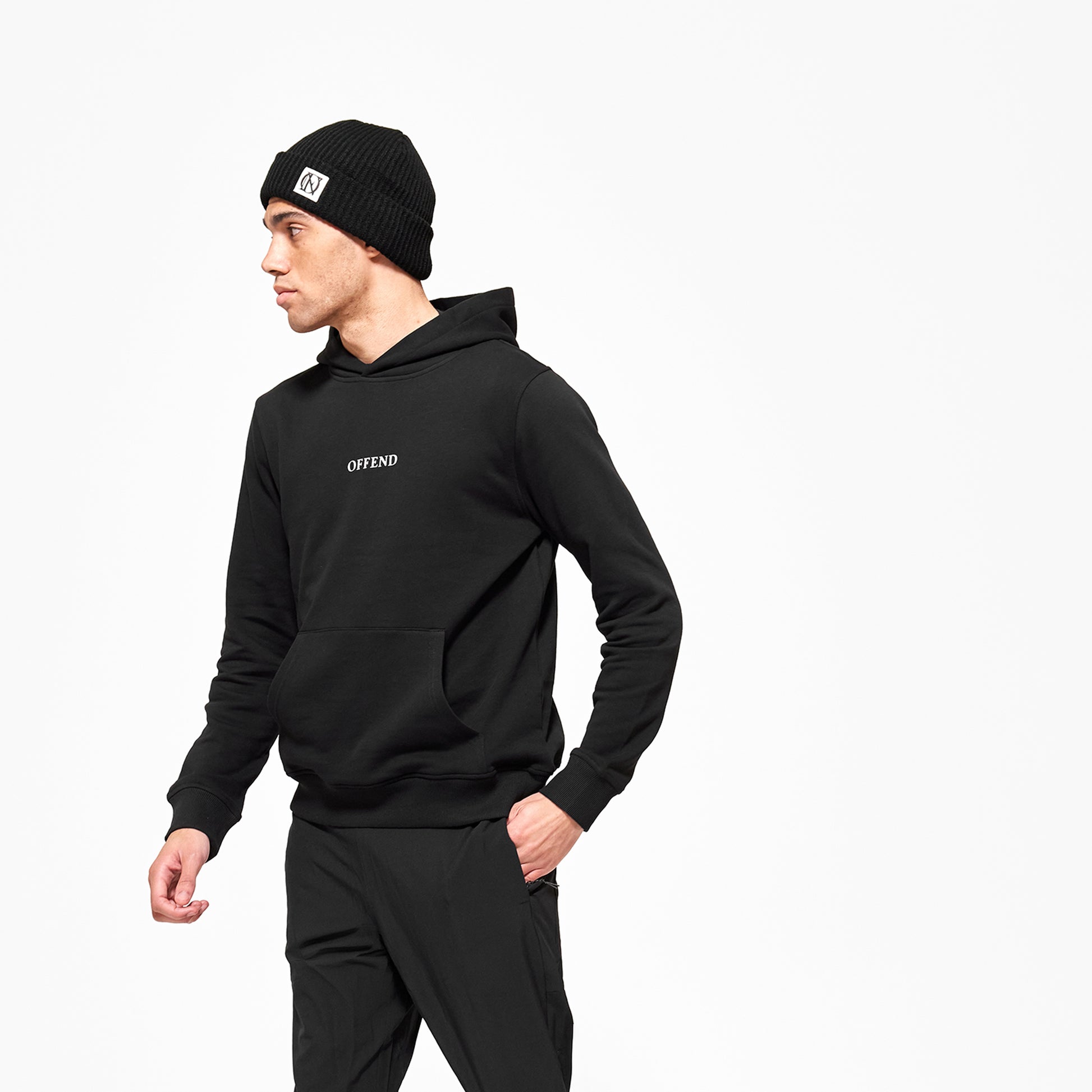 Model wearing 'OFFEND' black hoodie with 'OFFEND' text across centre of chest, model is also wearing 'OFFEND' black beanie with black 'OFFEND' logo on a white background