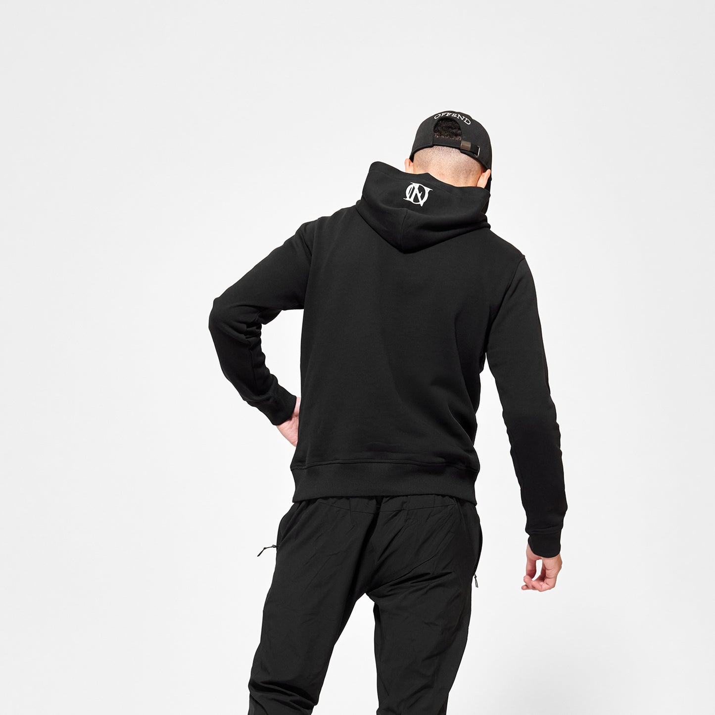 Model wearing Black 'OFFEND' hoodie with white 'OFFEND' logo on the centre of the hood, also wearing 'OFFEND' baseball cap with'OFFEND' text across back of cap on a white background